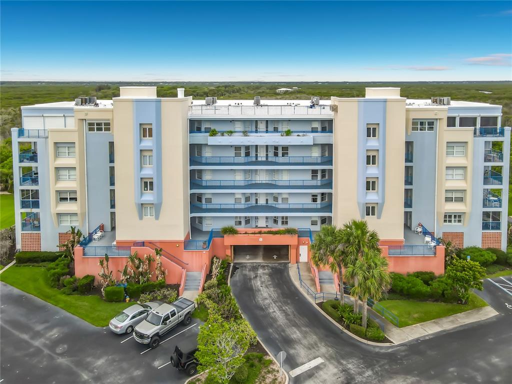 An exterior view of a multi-story apartment building with a ground-level parking garage entrance — 5300 S ATLANTIC AVENUE UNIT 5-301, NEW SMYRNA BEACH, FL