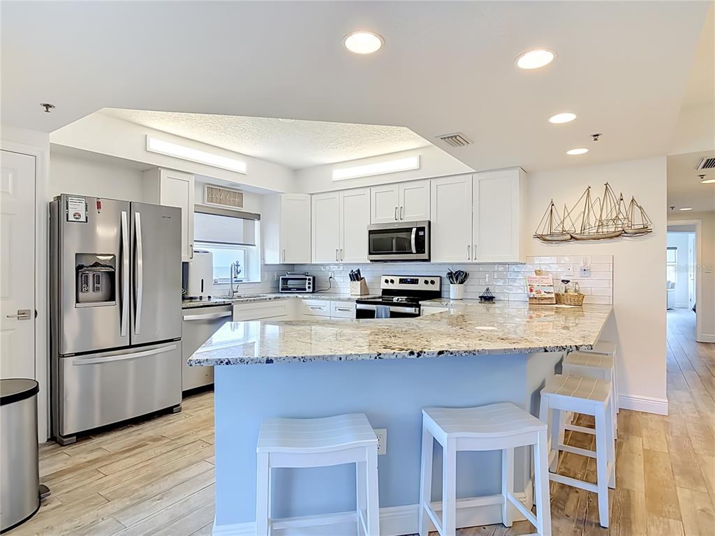 A kitchen with white cabinets, granite countertops, stainless steel appliances, and a breakfast bar — 5300 S ATLANTIC AVENUE UNIT 5-301, NEW SMYRNA BEACH, FL