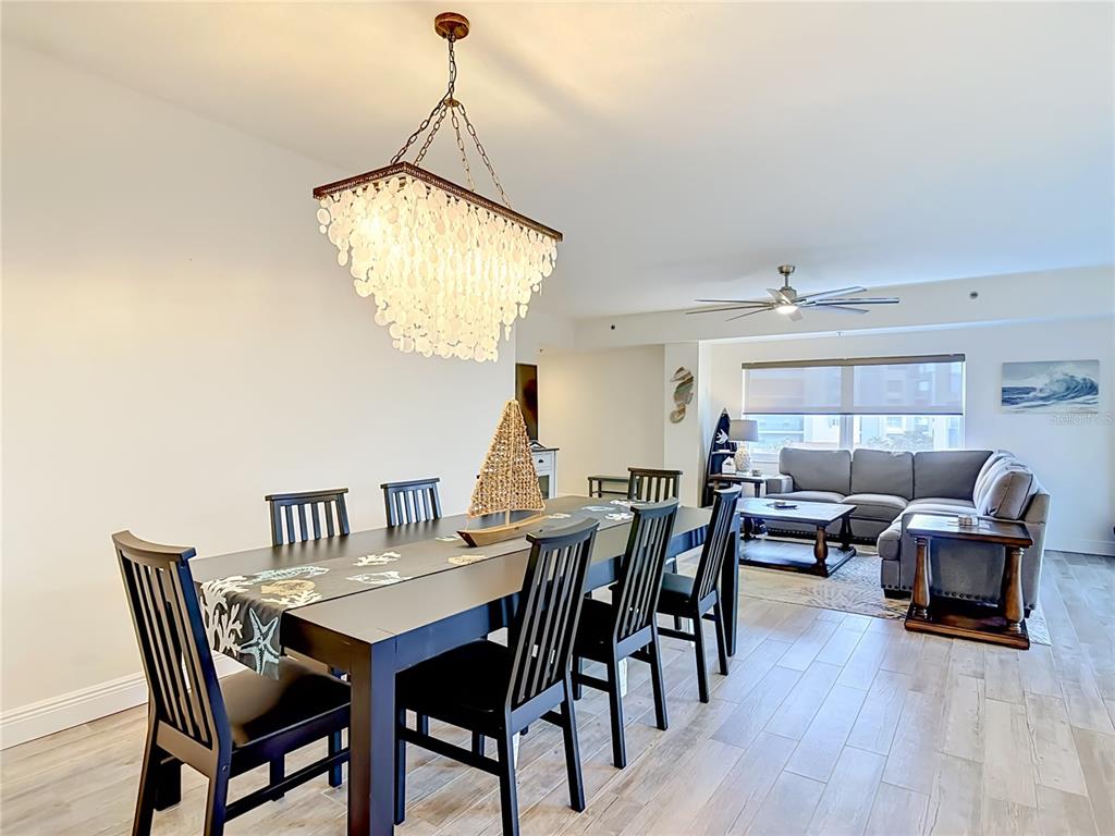 A dining area with a shell chandelier opens into a living room with gray furniture — 5300 S ATLANTIC AVENUE UNIT 5-301, NEW SMYRNA BEACH, FL