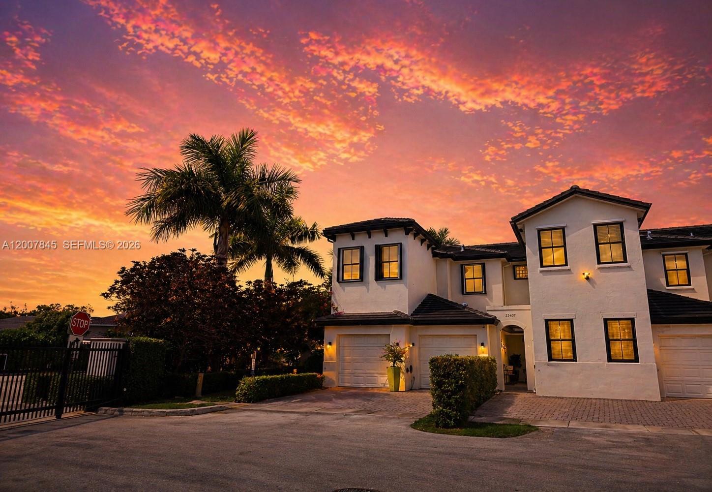 A two-story stucco house with a multi-car garage stands under a vibrant sunset sky — 22405 SW 102nd Ave, Miami FL 33190, MIAMI, FL