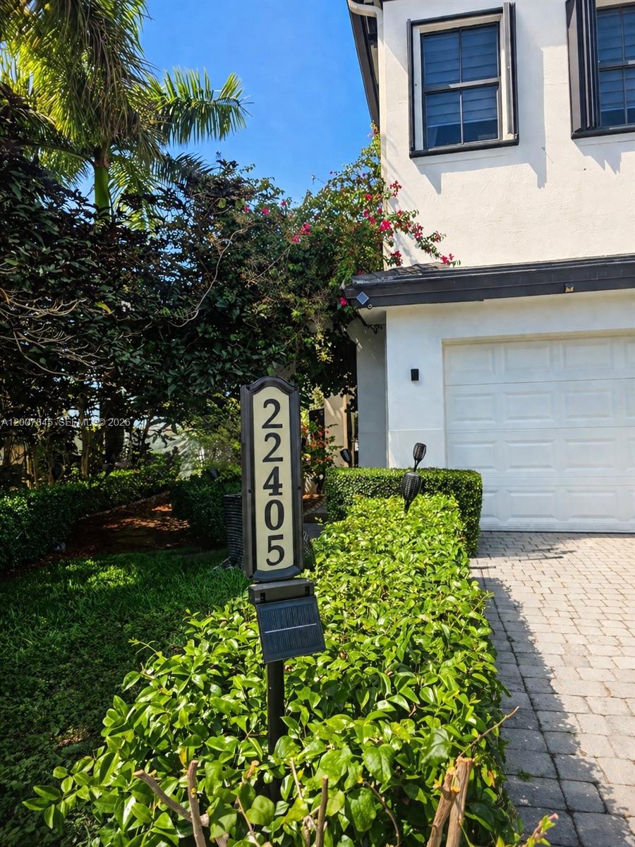 A vertical house number sign stands in front of a hedge and a white building — 22405 SW 102nd Ave, Miami FL 33190, MIAMI, FL