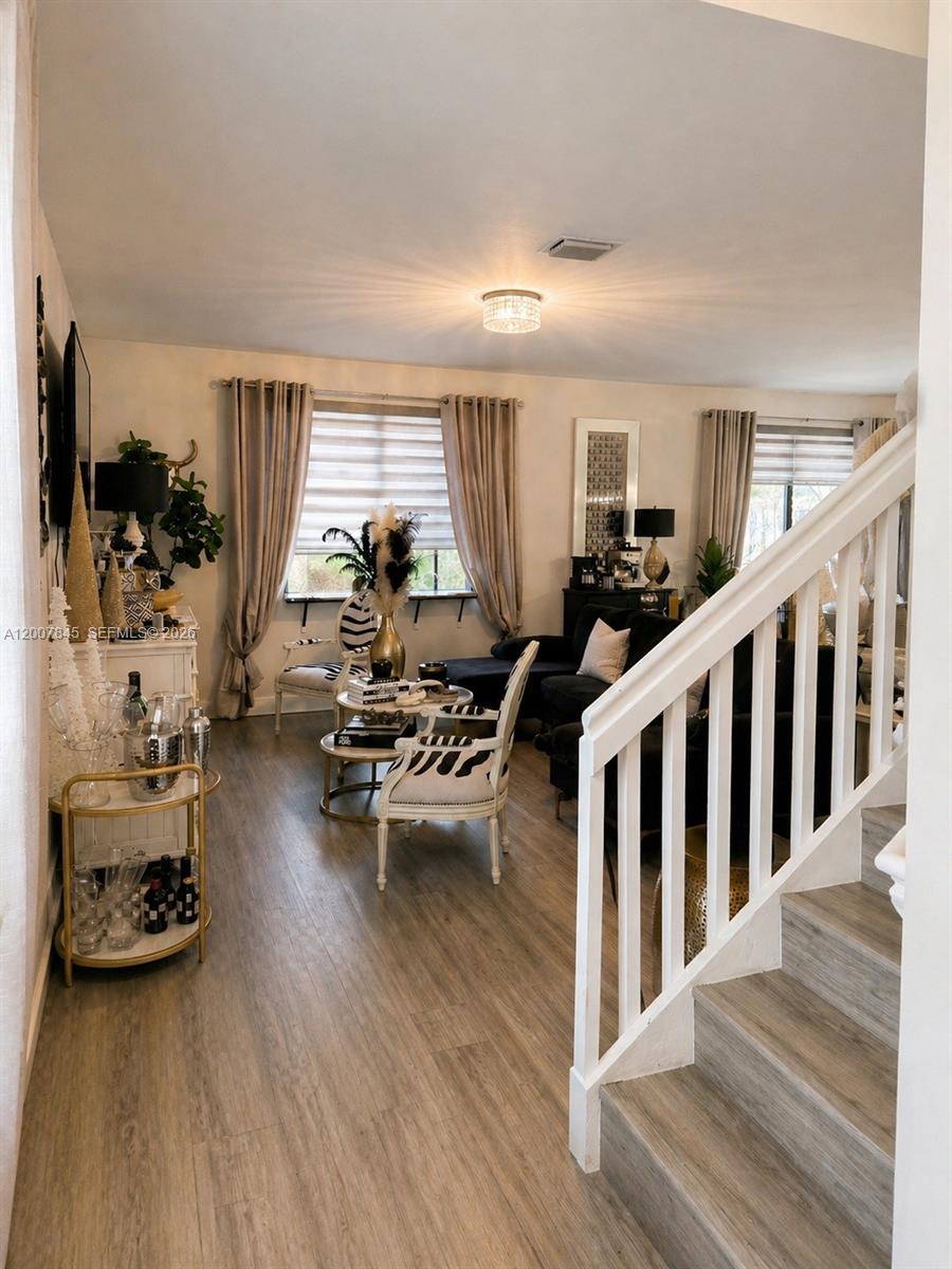 A living room features wood-look flooring, a staircase with white railings, and zebra-print chairs — 22405 SW 102nd Ave, Miami FL 33190, MIAMI, FL