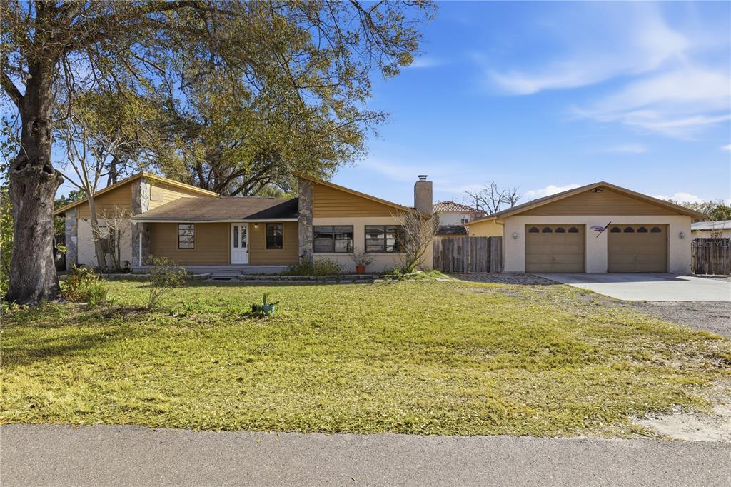 A single-story house with tan siding, stone accents, and an attached two-car garage — 10301 TRAIL RIDGE LANE, TAMPA, FL