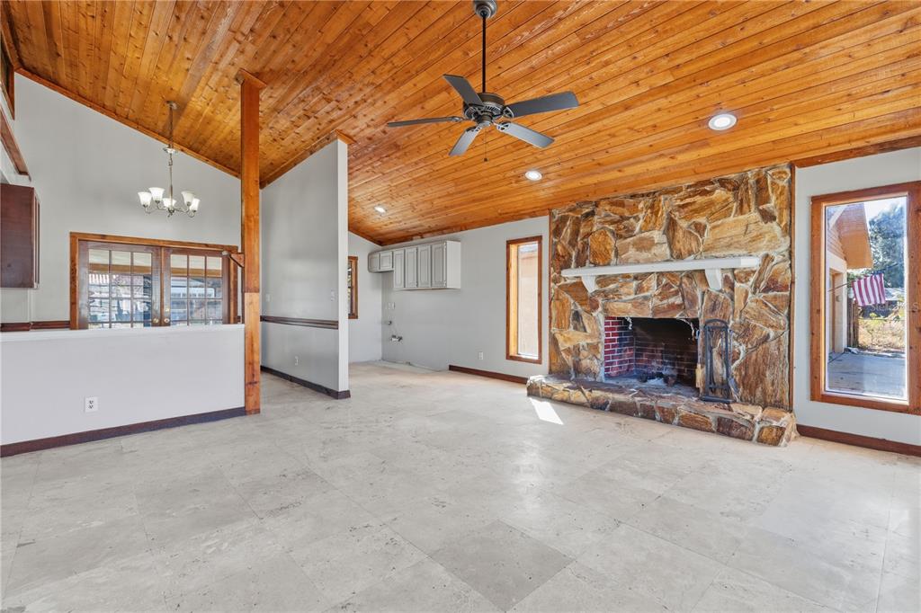 A living room with a stone fireplace, wood-plank ceiling, and light-colored tile flooring — 10301 TRAIL RIDGE LANE, TAMPA, FL