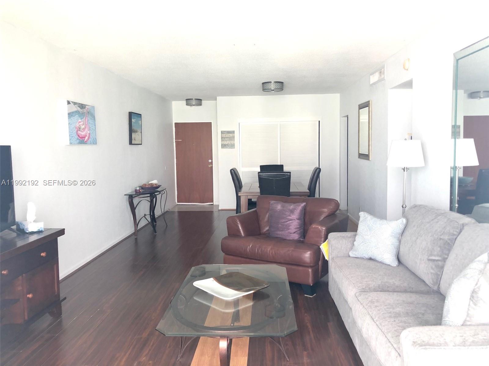 A living room with dark wood floors, a gray sofa, and a brown leather armchair — 3901 S Ocean Dr # 15C, Hollywood FL 33019, HOLLYWOOD, FL