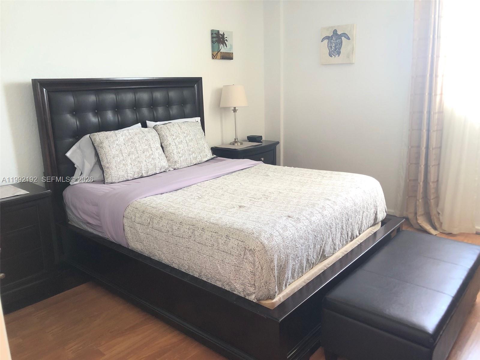A bedroom features a dark tufted headboard, a patterned bedspread, and a matching storage bench — 3901 S Ocean Dr # 15C, Hollywood FL 33019, HOLLYWOOD, FL