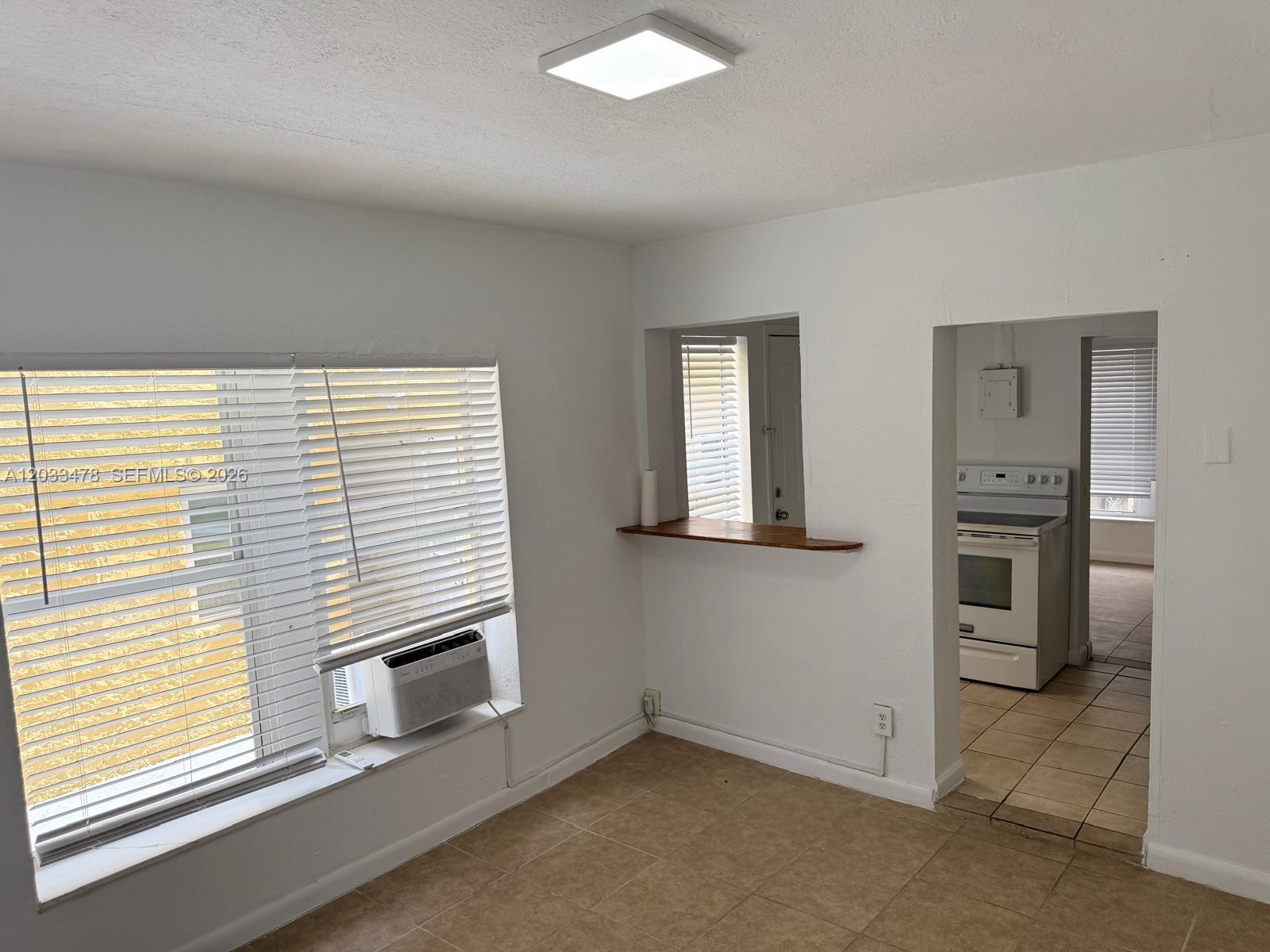 A room with tile flooring, a window air conditioner, and a pass-through to the kitchen — 1612 Harrison St # 5, Hollywood FL 33020, HOLLYWOOD, FL