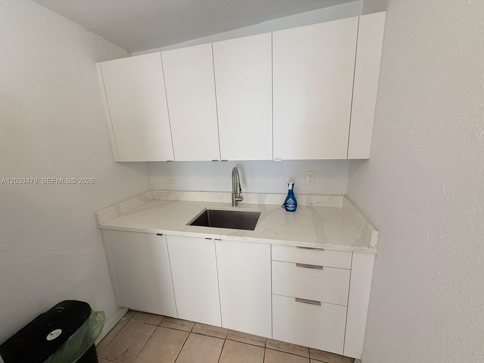 A small kitchen area features white cabinets, a stainless steel sink, and marble-patterned countertops — 1612 Harrison St # 5, Hollywood FL 33020, HOLLYWOOD, FL