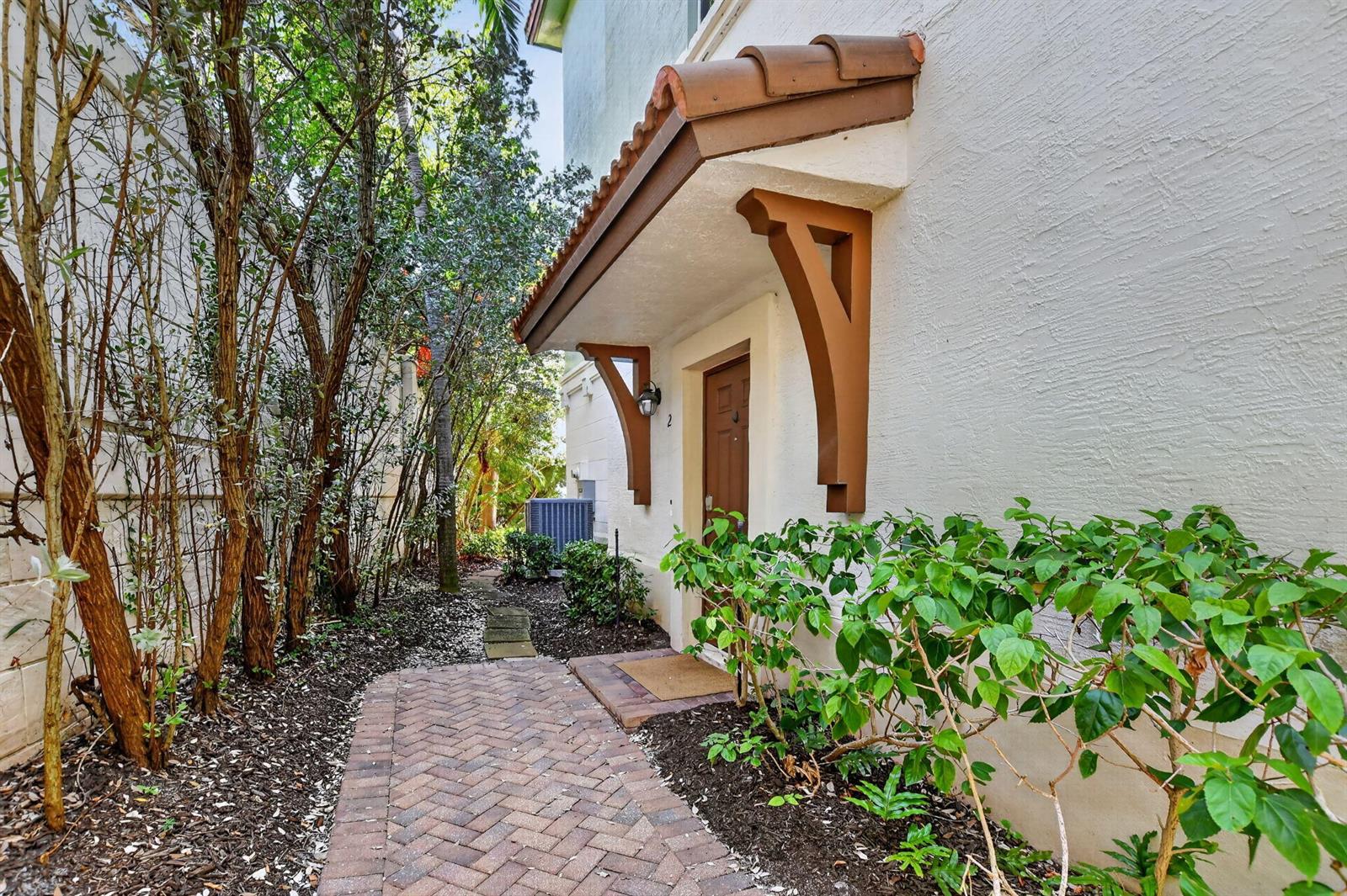 A brick walkway leads to a brown front door sheltered by a tiled awning — 27 NW Hawthorne Place, Boca Raton FL 33432, BOCA RATON, FL