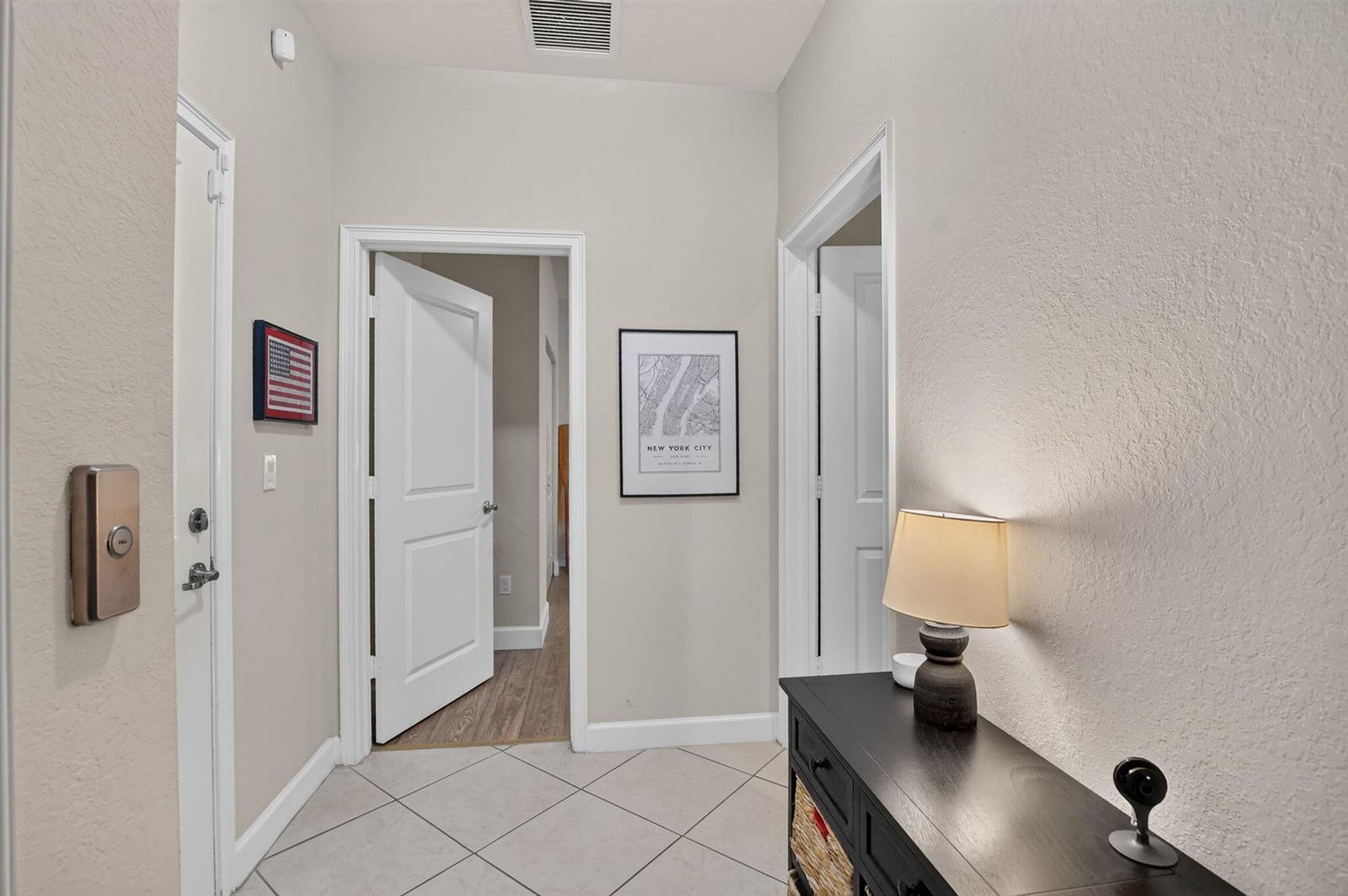 A hallway with tiled floors, a console table, and two doorways leading to other rooms — 27 NW Hawthorne Place, Boca Raton FL 33432, BOCA RATON, FL