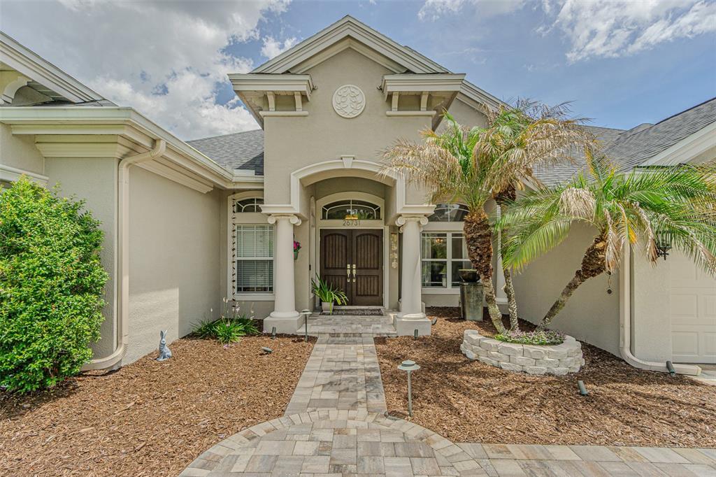 A paved walkway leads to the front entrance of a house with a palm tree — 26731 WINGED ELM DRIVE, WESLEY CHAPEL, FL