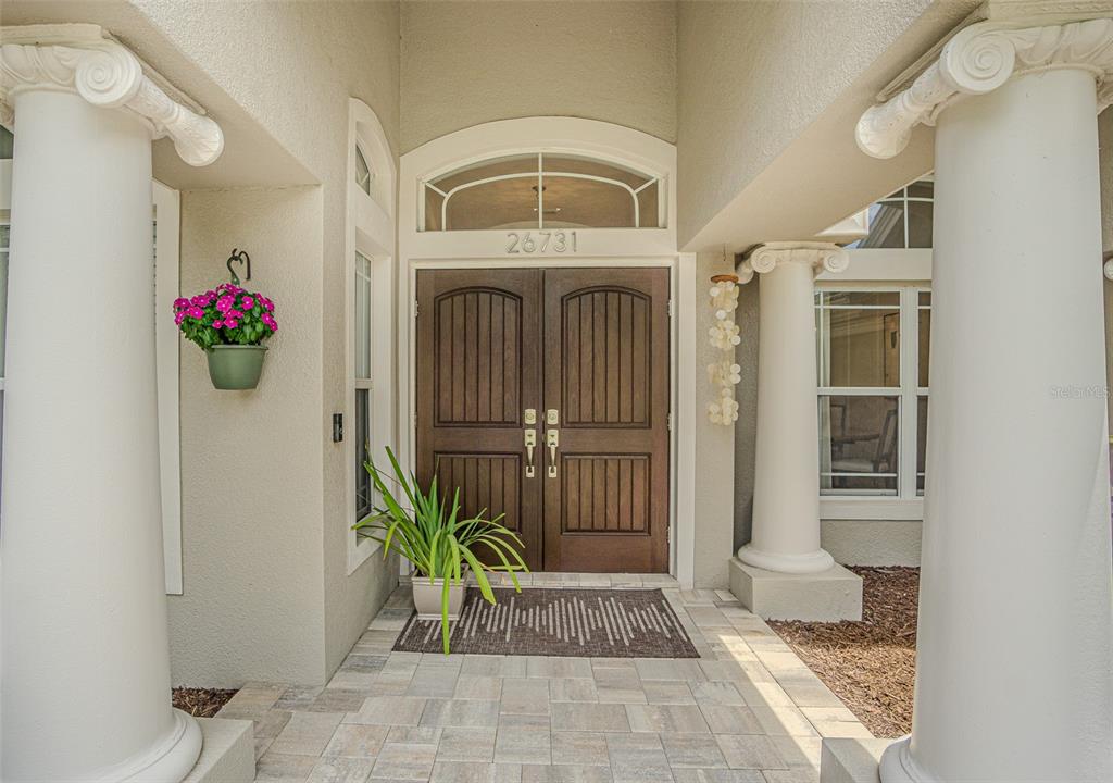 A front entryway features double wooden doors, two white columns, and a paved porch — 26731 WINGED ELM DRIVE, WESLEY CHAPEL, FL