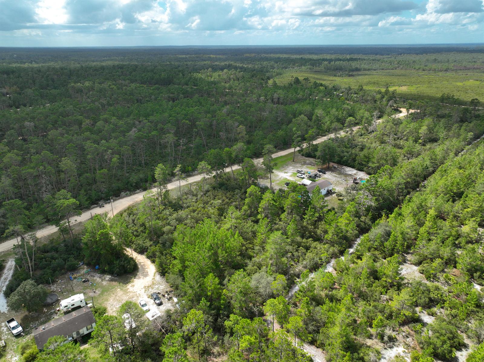 An aerial view shows two homes situated on large, wooded lots along a dirt road — 108 Morningside Drive, FL 32140, FL
