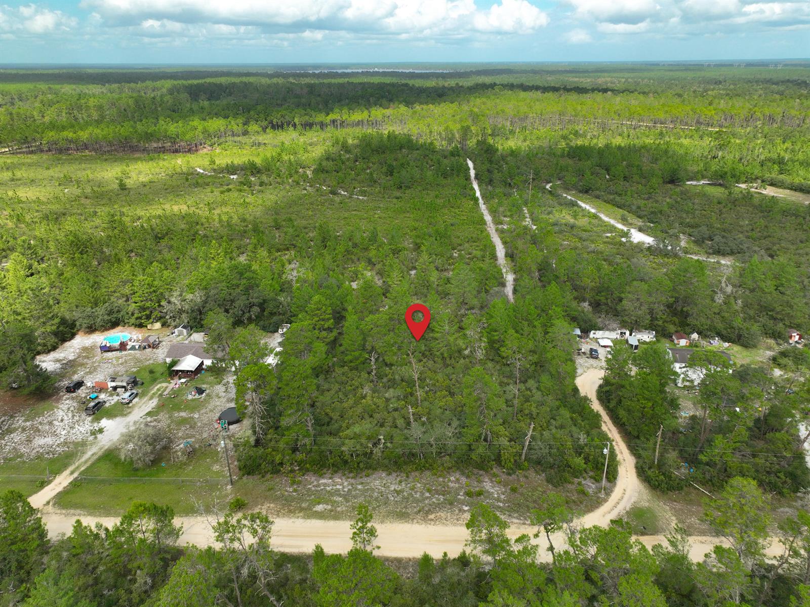 An aerial view shows a red map pin marking a wooded lot near dirt roads — 108 Morningside Drive, FL 32140, FL