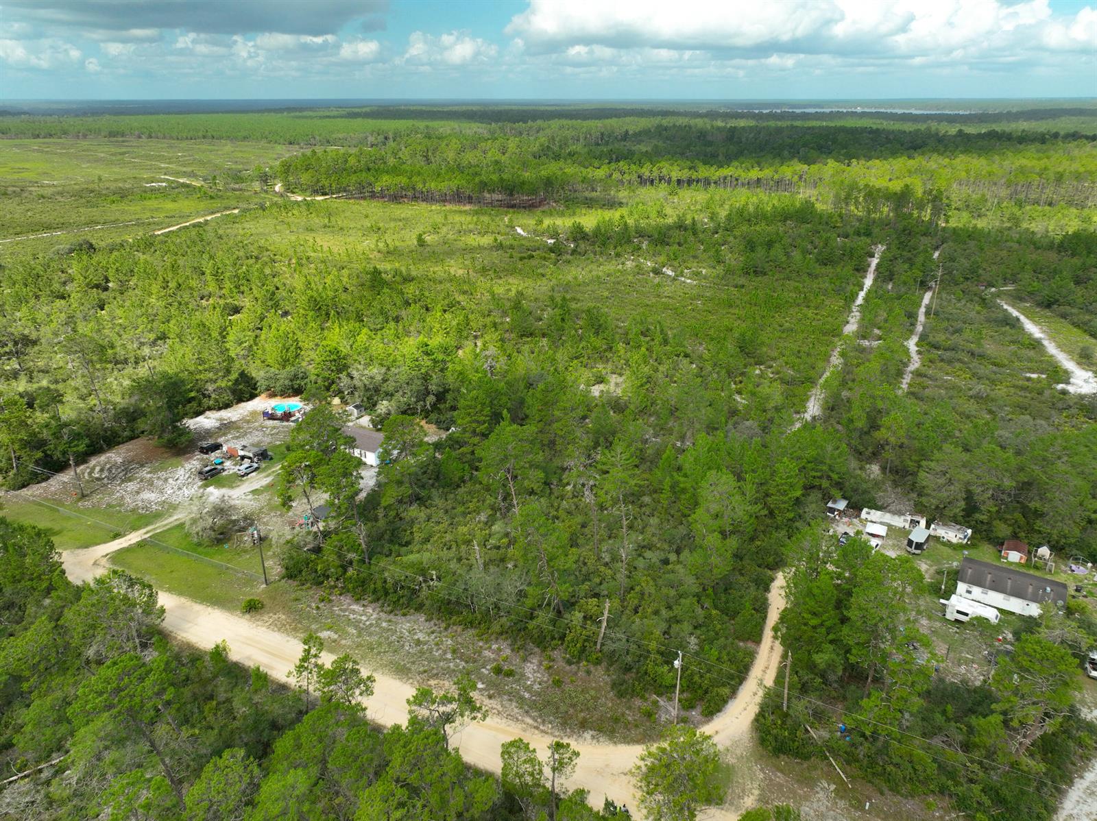An aerial view shows a rural property with two homes, a pool, and dirt roads — 108 Morningside Drive, FL 32140, FL