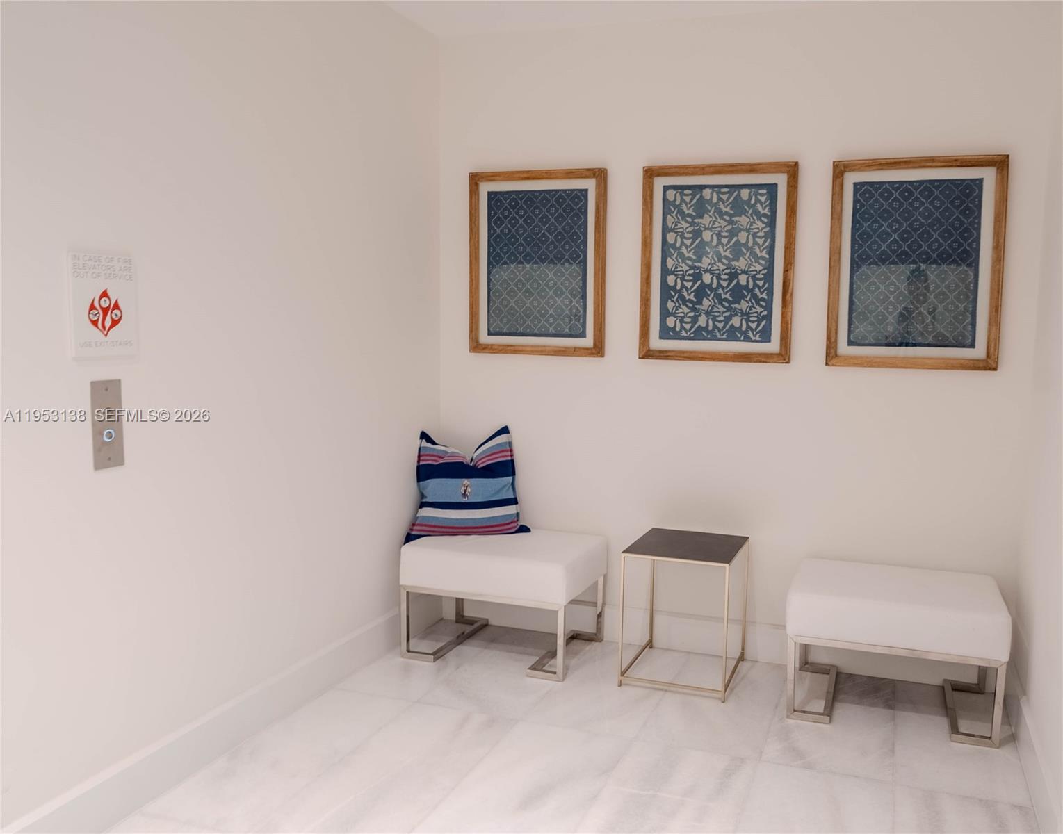 A white-walled hallway features two white benches, a small side table, and three framed prints — 700 NE 26th Ter # 2602, Miami FL 33137, MIAMI, FL