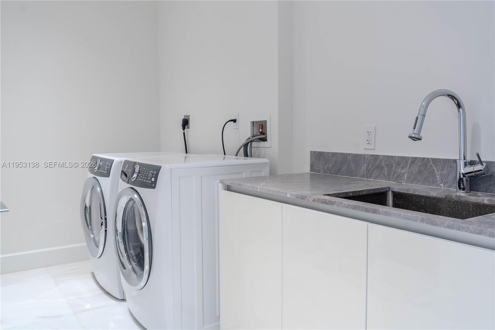 A laundry room features white appliances, a gray stone countertop, and a stainless steel sink — 700 NE 26th Ter # 2602, Miami FL 33137, MIAMI, FL