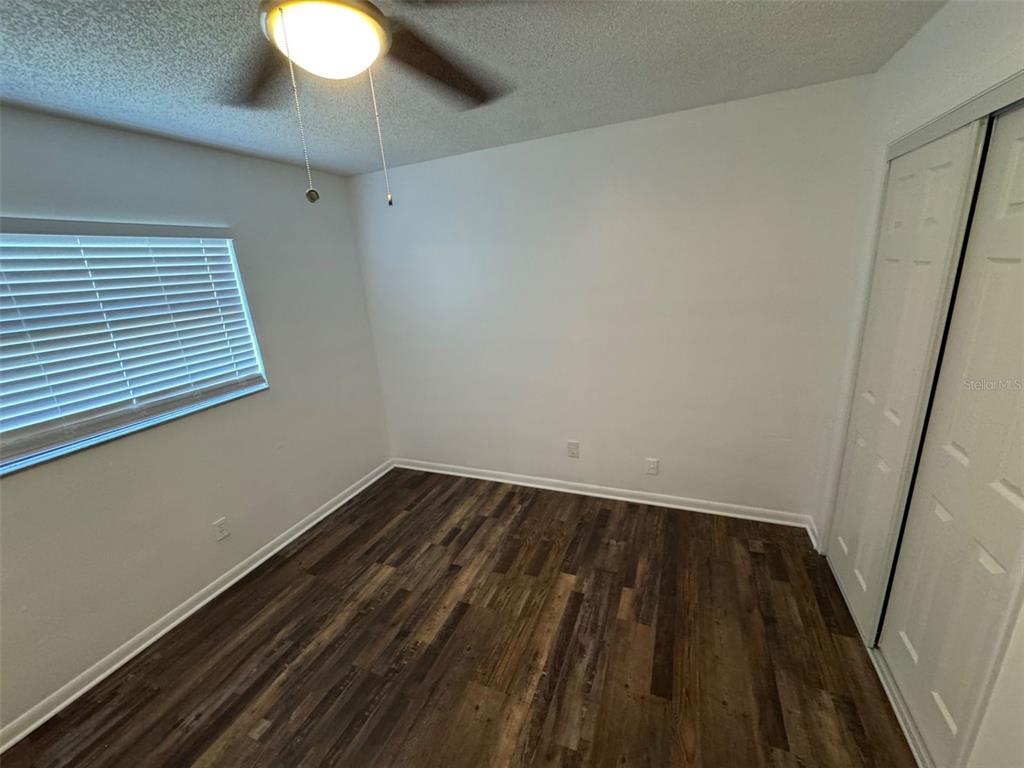 An empty bedroom features wood-look flooring, white walls, a ceiling fan, and a closet — 4851 16TH STREET, ZEPHYRHILLS, FL
