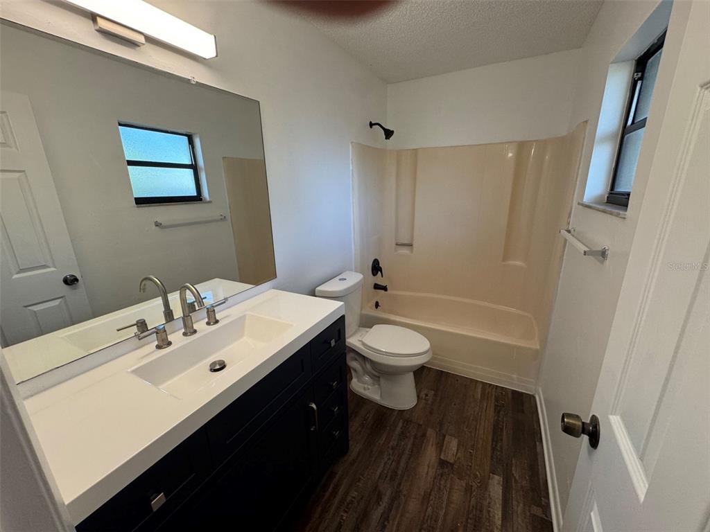 A bathroom features a dark vanity with a white countertop, a toilet, and a tub-shower — 4851 16TH STREET, ZEPHYRHILLS, FL