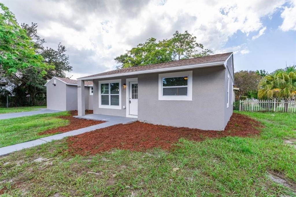 A gray, single-story house with a white door and windows sits on a grassy lot — 2001 45TH STREET S, ST PETERSBURG, FL