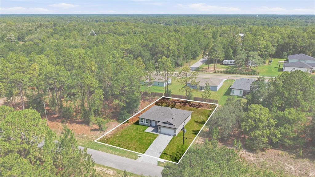 An aerial view shows a single-story house with a gray roof on a grassy lot — 1985 W CORRINE STREET, DUNNELLON, FL