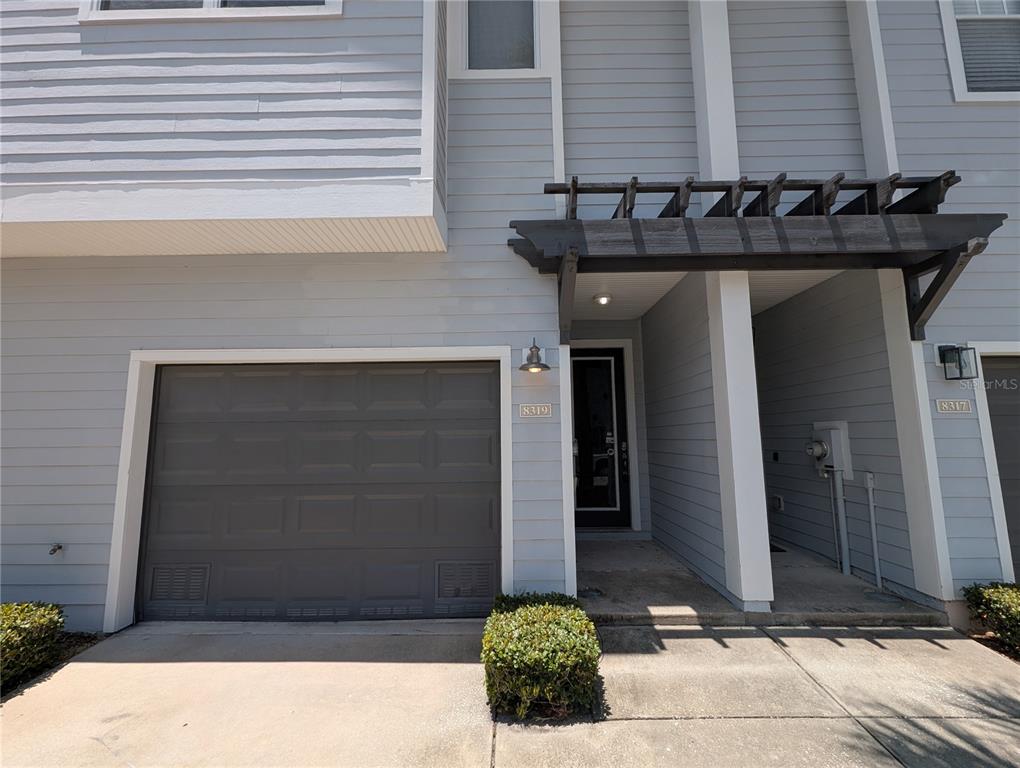 The exterior of a gray, two-story townhouse features a garage and a covered entryway — 8319 KING BLOSSOM COURT, TAMPA, FL