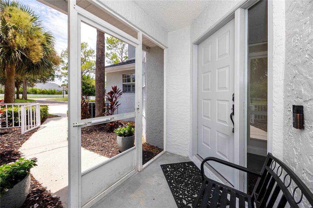 A white front door opens onto a concrete porch enclosed by a screen door — 1966 PLANTATION BOULEVARD, CLEARWATER, FL