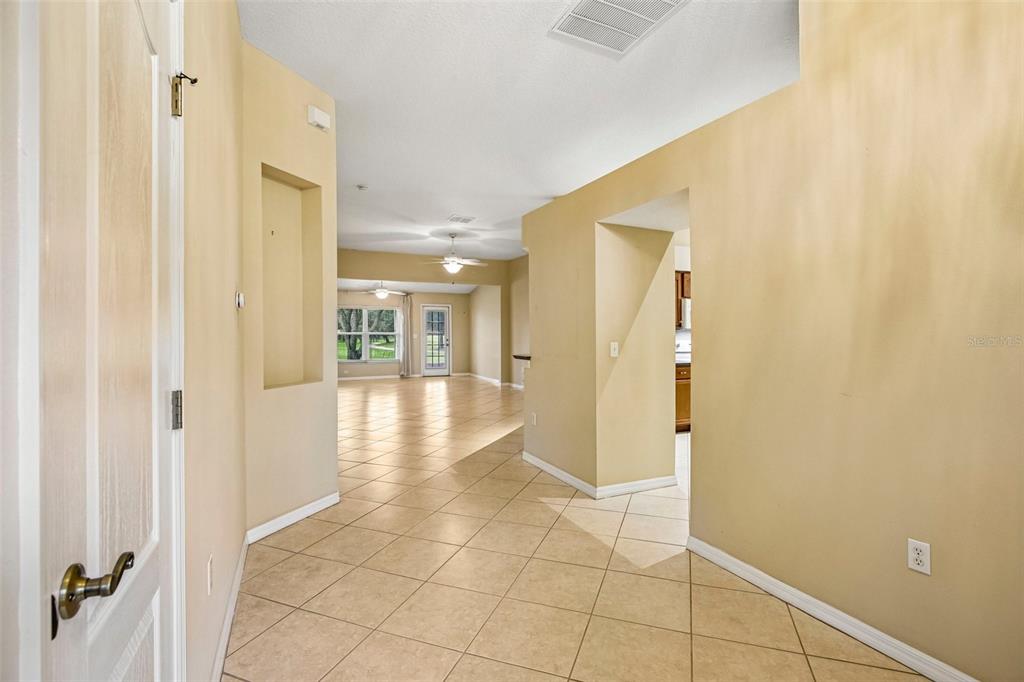 A tiled entryway leads into a living area with a ceiling fan and glass door — 2008 GRANTHAM GREENS DRIVE, SUN CITY CENTER, FL
