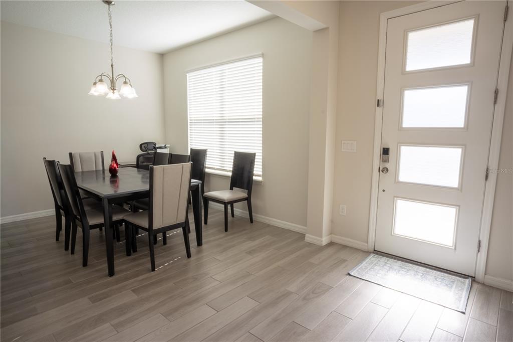 A dining room features a dark wood table, six chairs, a chandelier, and light wood flooring — 16461 OLIVE HILL DRIVE, WINTER GARDEN, FL