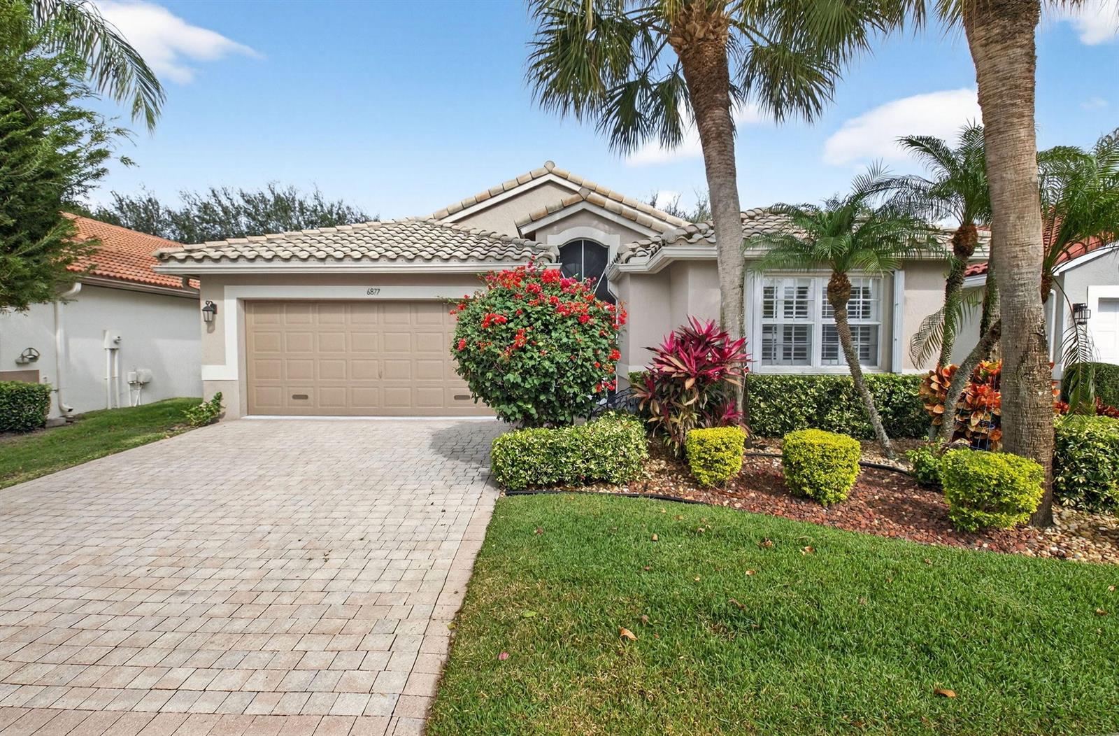 A single-story house with a beige stucco exterior, a tiled roof, and a paved driveway — 6877 Castlemaine Avenue, Boynton Beach FL 33437, BOYNTON BEACH, FL