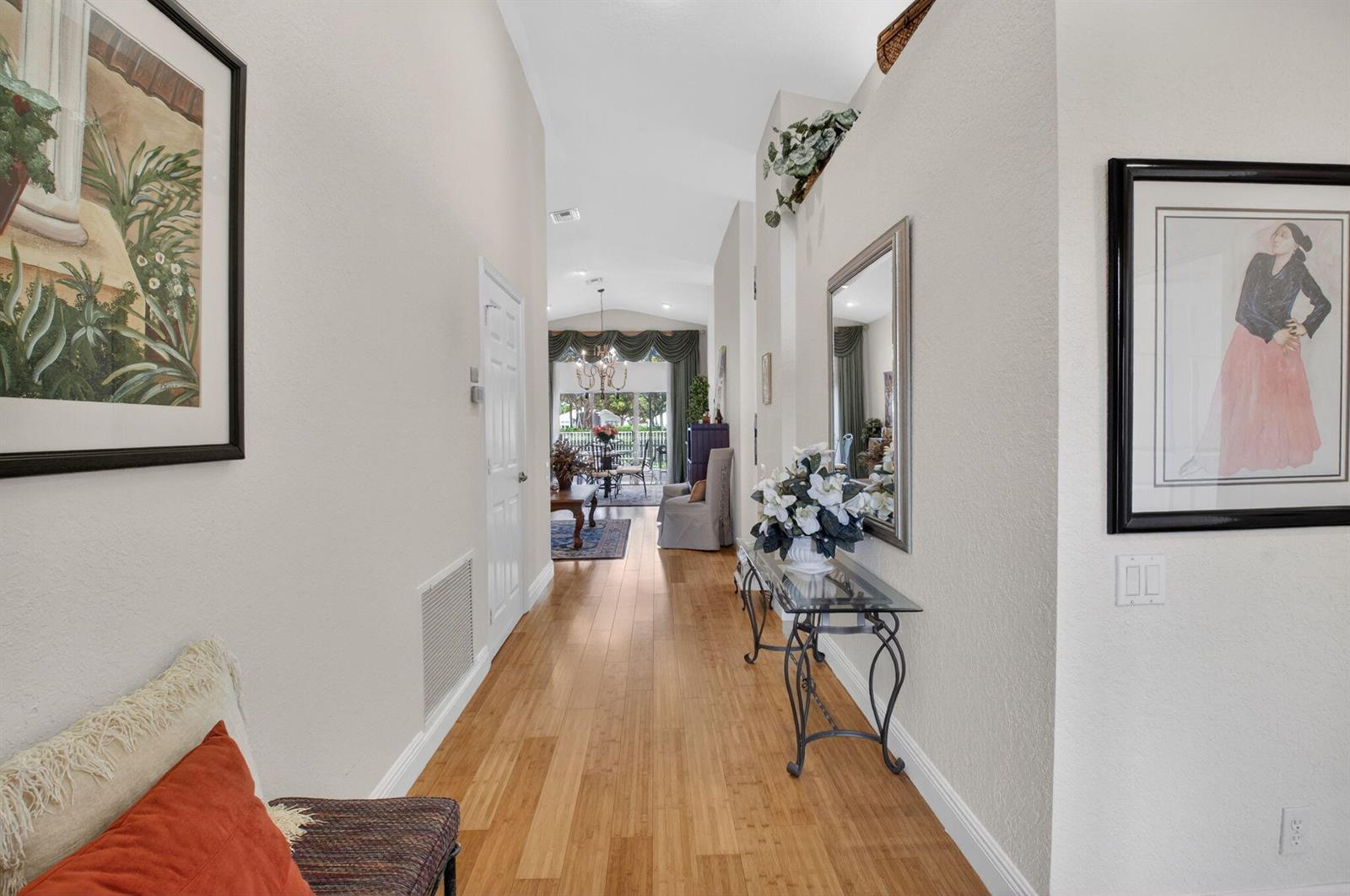 A hallway with hardwood floors leads toward a living area with a view of outdoors — 6877 Castlemaine Avenue, Boynton Beach FL 33437, BOYNTON BEACH, FL