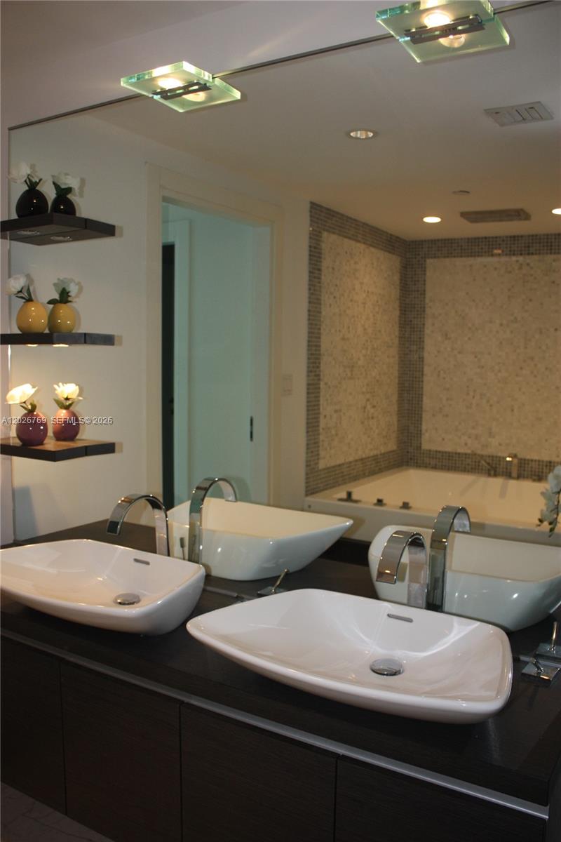 A modern bathroom features a double vanity with vessel sinks and a large soaking tub — 200 Biscayne Boulevard Way # 4211, Miami FL 33131, MIAMI, FL