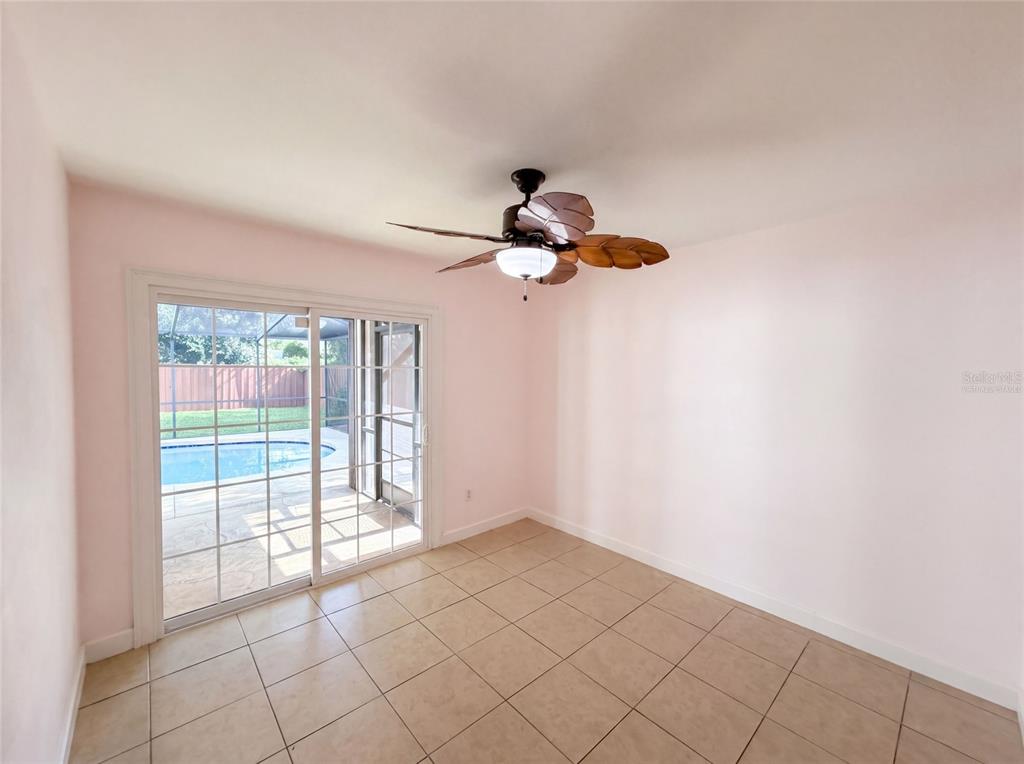 A room with light pink walls, tile flooring, a ceiling fan, and sliding glass doors — 7233 THOMAS JEFFERSON CIRCLE W, BARTOW, FL