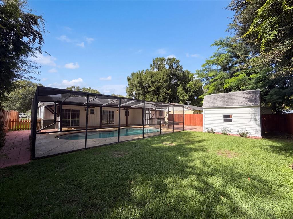 A backyard features a screened-in pool, a small white shed, and a grassy lawn — 7233 THOMAS JEFFERSON CIRCLE W, BARTOW, FL