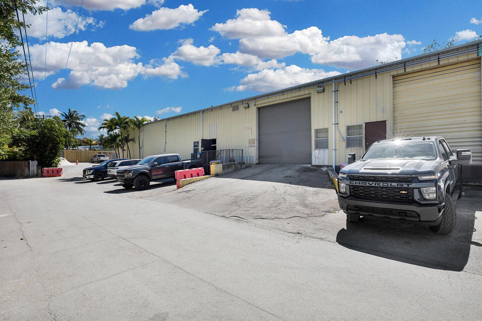 A gray pickup truck is parked in front of a warehouse with a roll-up door — 210 Industrial Drive, Islamorada FL 33036, ISLAMORADA, FL