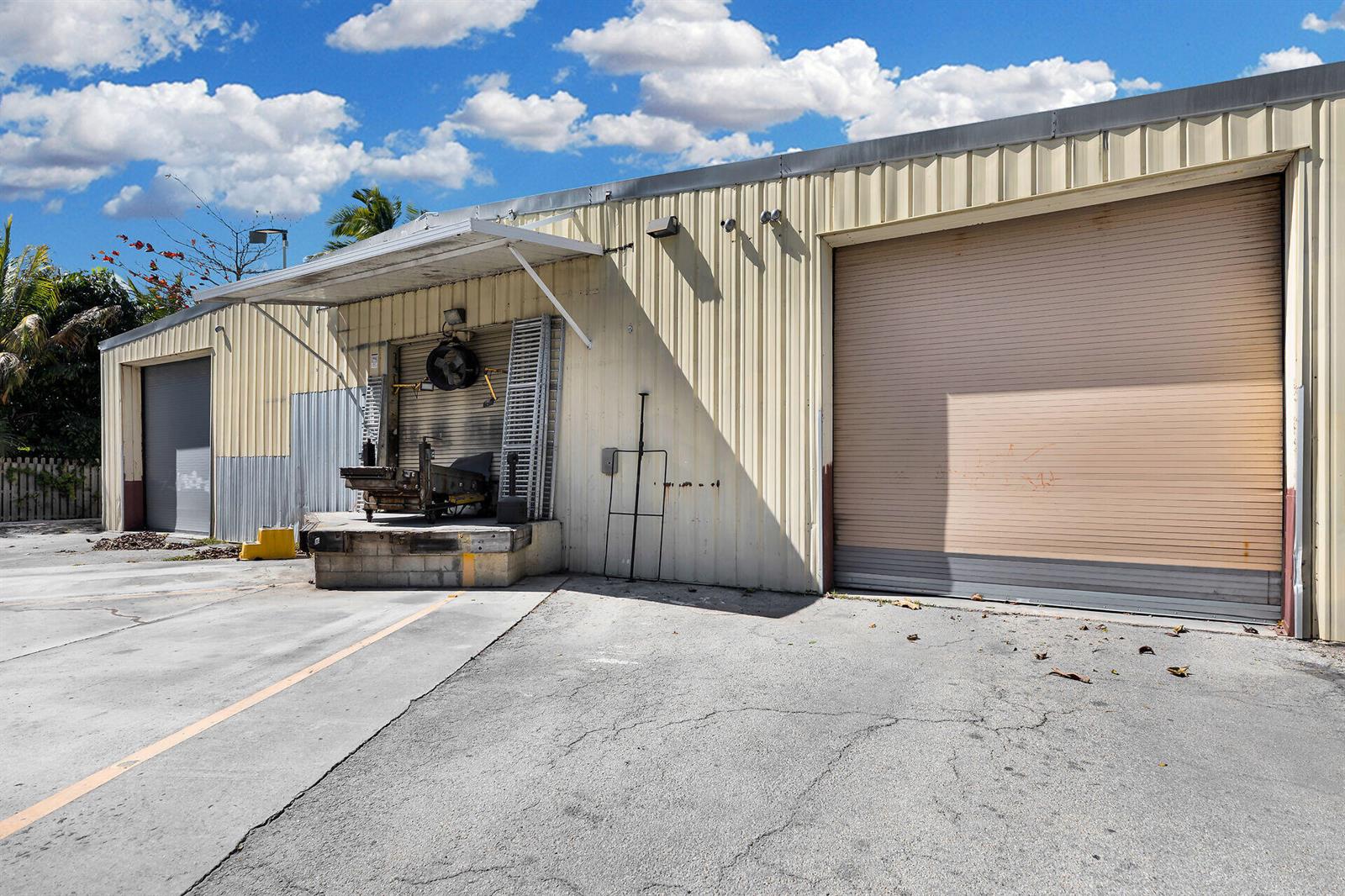 An exterior view of a metal warehouse building featuring a loading dock and roll-up doors — 210 Industrial Drive, Islamorada FL 33036, ISLAMORADA, FL