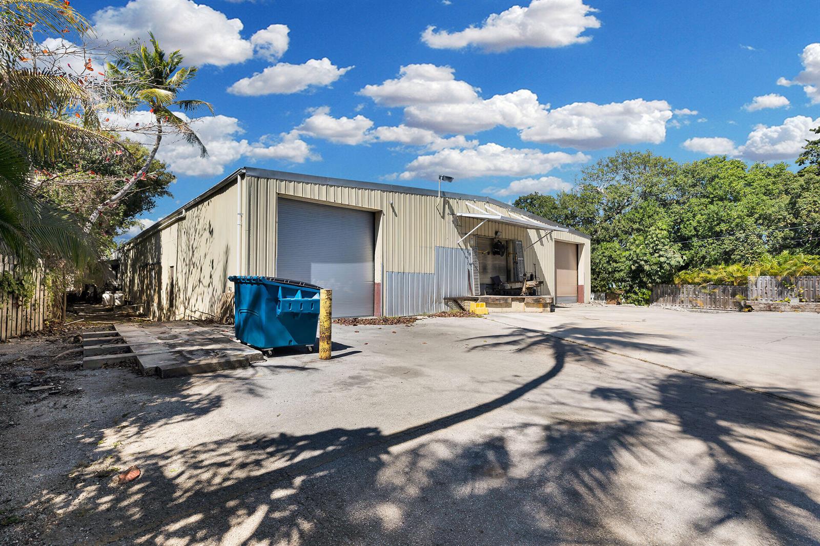 An exterior view of a metal warehouse building with two roll-up doors and a dumpster — 210 Industrial Drive, Islamorada FL 33036, ISLAMORADA, FL