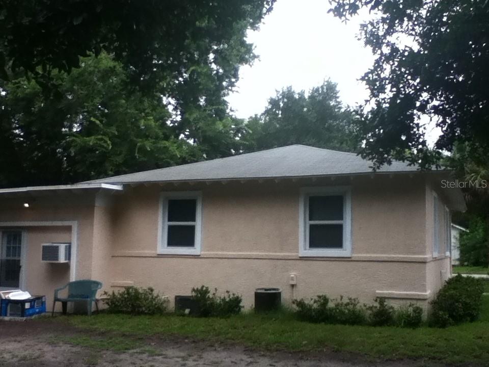 A side view of a single-story house with tan stucco siding and a hip roof — 486 OAK STREET, NEW SMYRNA BEACH, FL