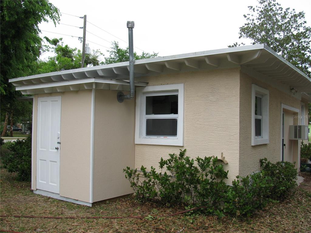 A beige, single-story exterior with a white door, two windows, and a metal vent pipe — 486 OAK STREET, NEW SMYRNA BEACH, FL