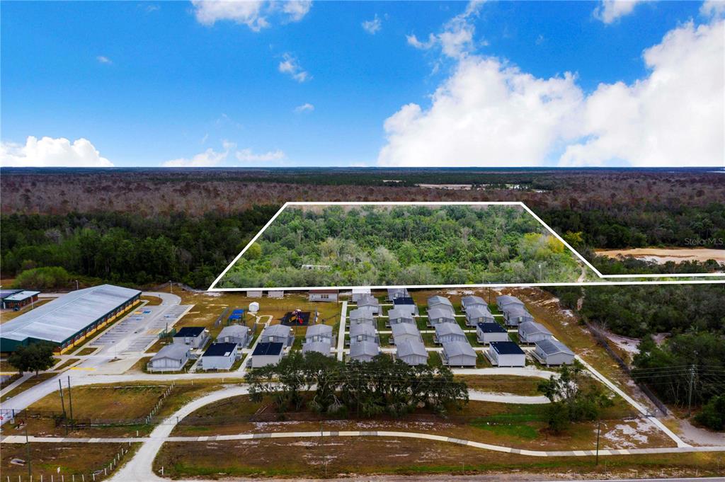 An aerial view shows a wooded lot outlined in white adjacent to a mobile home park — LAUREL AVENUE, POINCIANA, FL