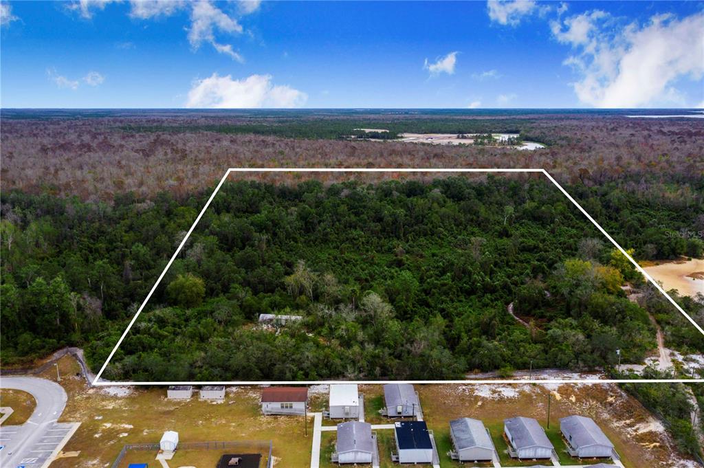 An aerial view shows a large, wooded rectangular lot outlined in white above residential homes — LAUREL AVENUE, POINCIANA, FL