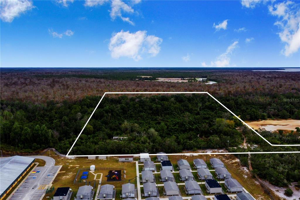 An aerial view shows a large, rectangular plot of wooded land adjacent to a neighborhood — LAUREL AVENUE, POINCIANA, FL
