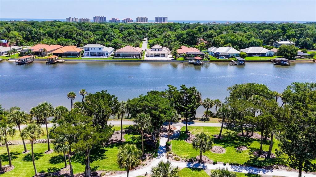 An aerial view shows houses along a canal with a park in the foreground — 50 PALM HARBOR PARKWAY UNIT 38, PALM COAST, FL
