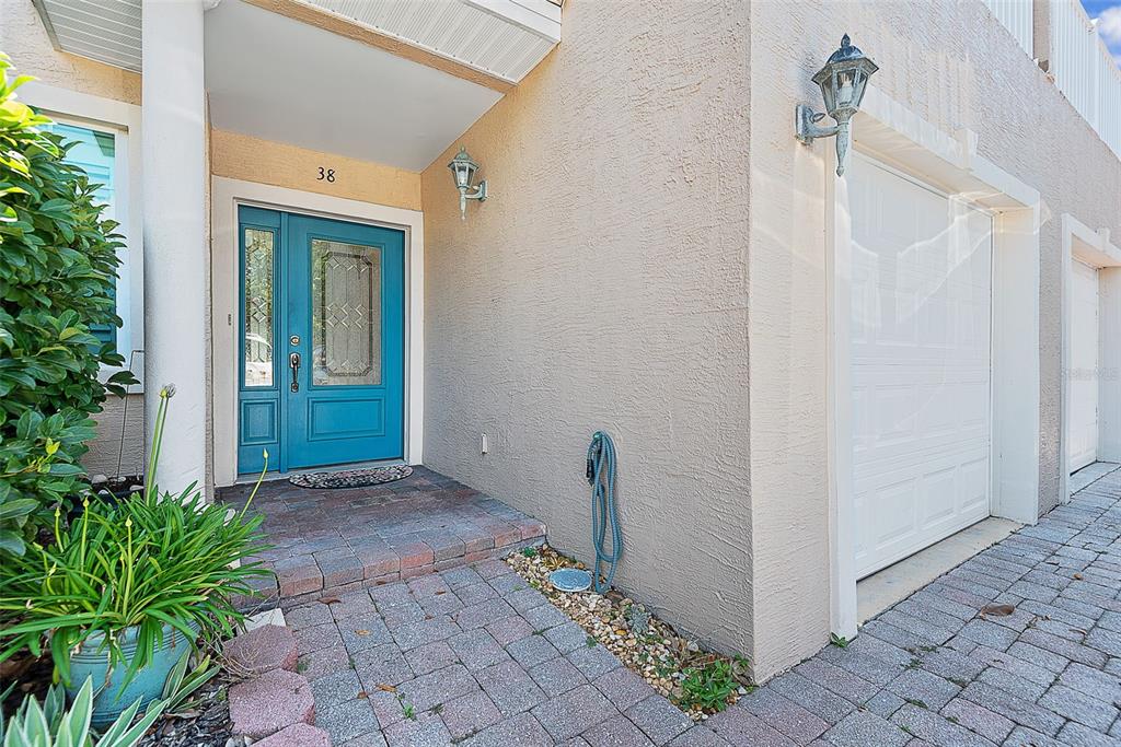 A teal front door with a glass insert sits next to a white garage door — 50 PALM HARBOR PARKWAY UNIT 38, PALM COAST, FL