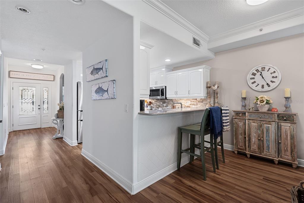 A kitchen with a breakfast bar, white cabinets, and a dining area with a wall clock — 50 PALM HARBOR PARKWAY UNIT 38, PALM COAST, FL