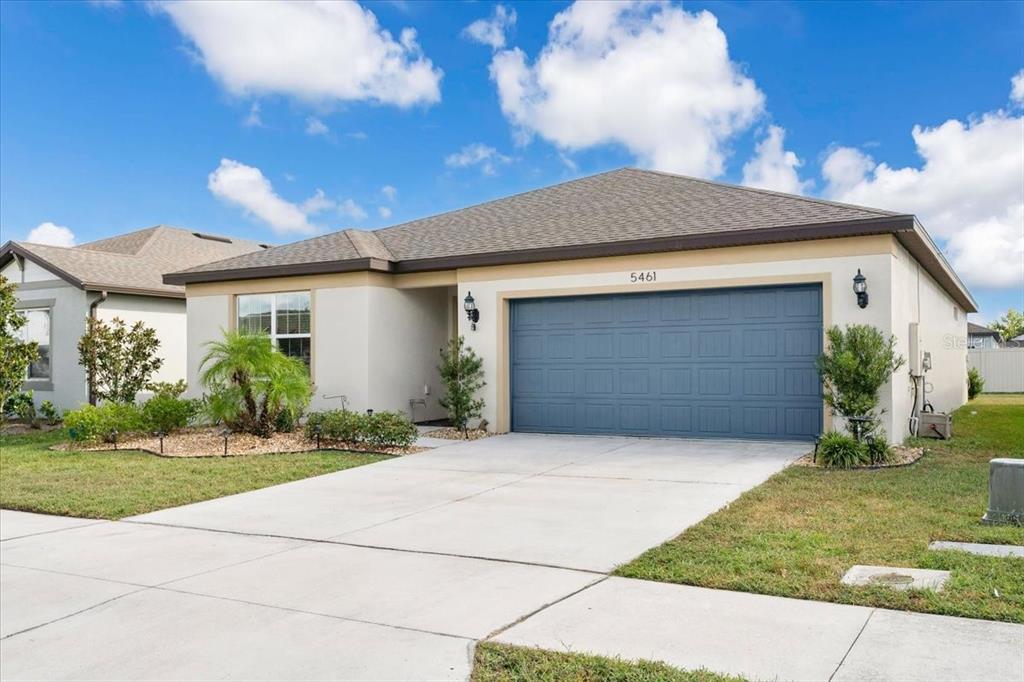 A single-story house with a blue garage door and a concrete driveway under a sky — 5461 KEATON SPRINGS DRIVE, LAKELAND, FL