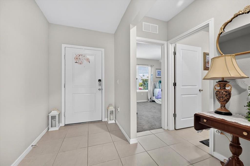 An entryway with tile flooring, a white front door, and a view into a bedroom — 5461 KEATON SPRINGS DRIVE, LAKELAND, FL