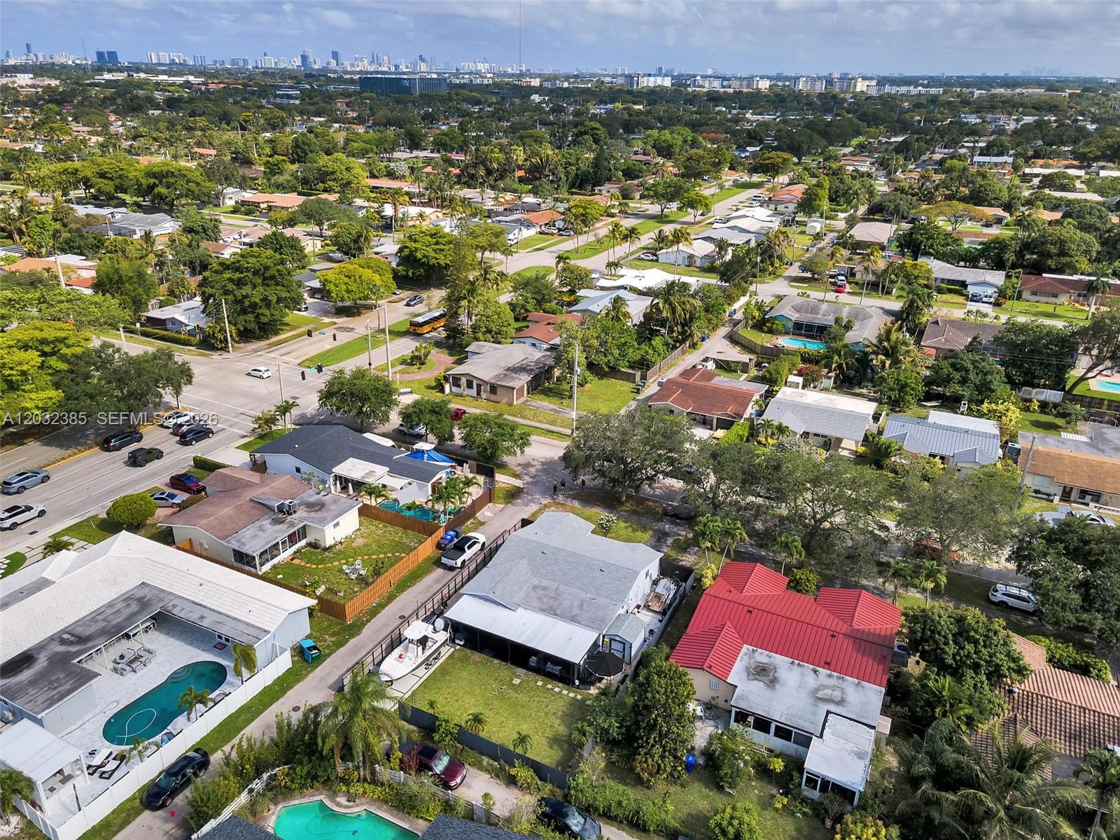 An aerial view shows a suburban neighborhood with houses, swimming pools, and tree-lined streets — 4621 Johnson St, Hollywood FL 33021, HOLLYWOOD, FL
