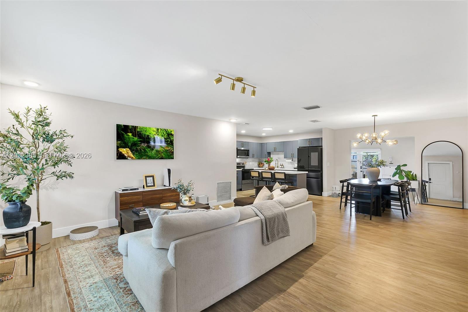 This open-concept living area features a light-colored sofa, a dining set, and a modern kitchen — 4621 Johnson St, Hollywood FL 33021, HOLLYWOOD, FL