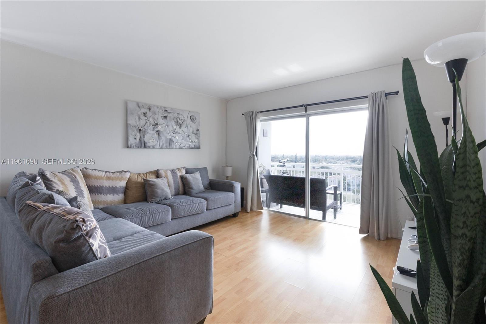 A living room features a grey sectional sofa, light wood flooring, and a sliding glass door — 4400 Hillcrest Dr # 901B, Hollywood FL 33021, HOLLYWOOD, FL